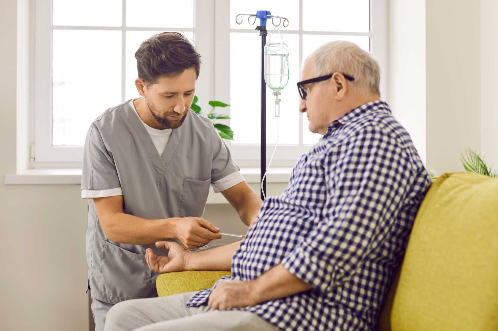 male nurse administering IV on elderly male patient on couch